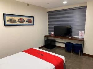 - une chambre avec un lit et un bureau avec une télévision dans l'établissement RedDoorz Plus @ Toshiko Boutique Hotel Koronadal City, à Koronadal