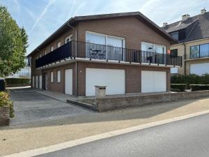 a brick house with two white garage doors at De Boei - Koksijde in Koksijde