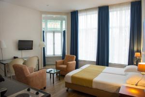 a hotel room with a bed and chairs and windows at Hotel Residence Le Coin in Amsterdam