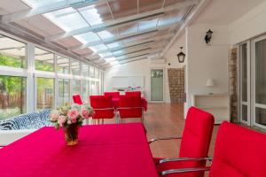 a room with red chairs and a table with a vase of flowers at Sylvia Ház in Tihany