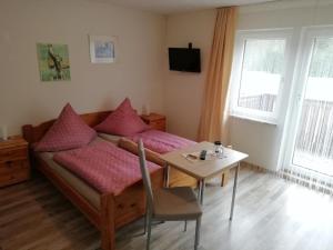 a bedroom with a bed and a table and a table and chair at Pension Fohlenhof in Frauenau