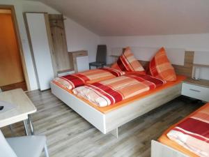 ein Schlafzimmer mit einem Bett mit orangefarbenen und braunen Kissen in der Unterkunft Pension Fohlenhof in Frauenau