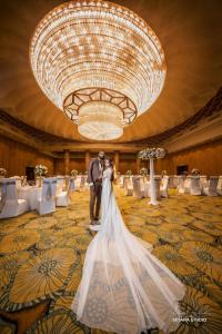 a bride and groom standing under a large chandelier at Hotel Royal Ramesses - Katunayake in Seeduwa