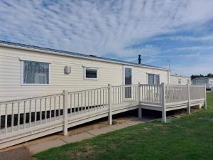 a white mobile home with a wooden deck at Manor at Manor Park Hunstanton WiFi pets go free in Hunstanton