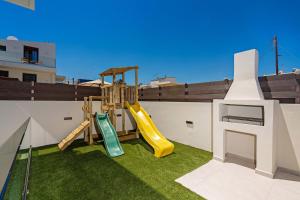 une cour avec une aire de jeux dotée d'un toboggan et d'herbe dans l'établissement Amara Villas, à Réthymnon 110 autres photos