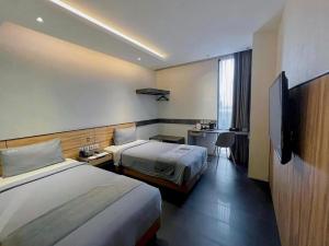 a hotel room with two beds and a desk at Erian Hotel in Jakarta