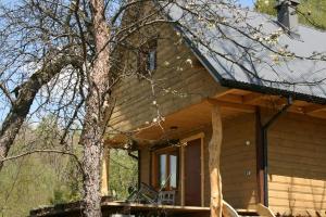 a log cabin with a porch and a tree at LESZCZYNOWY STOK in Lutowiska