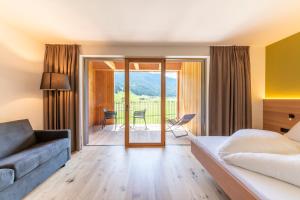 a hotel room with a bed and a couch at Hotel Tyrol in Valle Di Casies