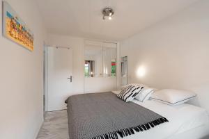 Dormitorio blanco con cama con almohadas blancas en Appartement 2 pièces au calme proche Martinez avec parking privé en Cannes