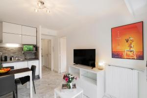 a living room with a television and a kitchen at Appartement 2 pièces au calme proche Martinez avec parking privé in Cannes