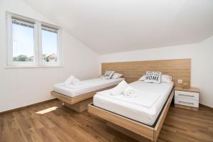 Ce lit se trouve dans un dortoir doté de murs blancs et de parquet. dans l'établissement Apartments Luka i Toni, à Vodice