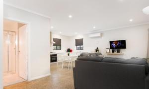 a living room with a black couch and a kitchen at Jalilla Village in Kingscote