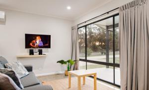 a living room with a couch and a tv on a wall at Jalilla Village in Kingscote