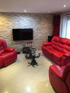 a living room with red couches and a flat screen tv at Willa Mateusza in Sandomierz