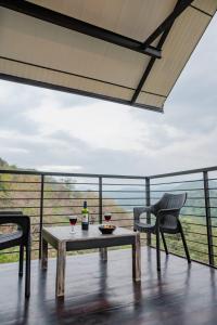 a table with two chairs and a bottle of wine on a balcony at Casa Del Sol - Luxury Villa in Bolepe