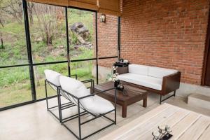 a living room with a couch and chairs and a brick wall at Casa Del Sol - Luxury Villa in Bolepe +42 photos