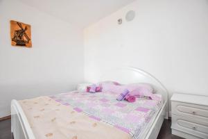 a white bed with a pink and purple quilt on it at House Mateo in Neviđane +23 photos