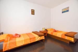 two beds with orange sheets in a room at House Mateo in Neviđane