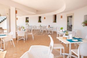 a restaurant with white tables and white chairs at Hotel L'Aragosta in La Caletta