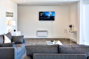 uma sala de estar com dois sofás e uma televisão na parede em Just Stay Wales - Meridian Tower Marina & City View - 2 Bed Apartment em Swansea