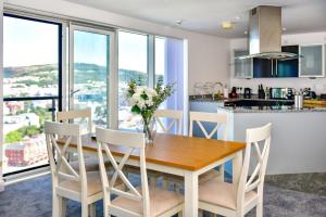 cocina y comedor con mesa y sillas en Just Stay Wales - Meridian Tower Marina & City View - 2 Bed Apartment, en Swansea