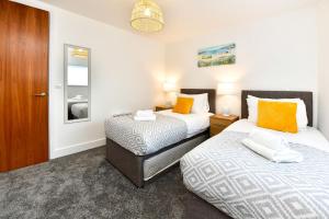 1 dormitorio con 2 camas y puerta en Just Stay Wales - Meridian Tower Marina & City View - 2 Bed Apartment en Swansea