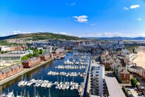 a city with boats docked in a harbor at Just Stay Wales - Meridian Tower Marina & City View - 2 Bed Apartment in Swansea