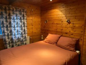 een slaapkamer met een bed met een houten muur bij Knus boshuisje middenin de natuur in Doldersum