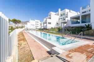 a swimming pool in front of a white building at 71-Beachfront, brand new luxury penthouse Benalmádena in Benalmádena