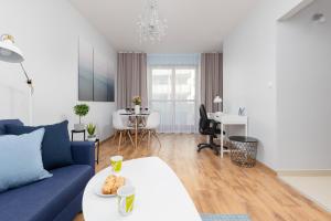 uma sala de estar com um sofá azul e uma mesa em Warsaw Bemowo Apartment with Balcony by Renters em Varsóvia