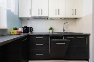 a kitchen with black and white cabinets and a sink at Warsaw Bemowo Apartment with Balcony by Renters in Warsaw