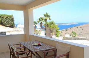 een balkon met een tafel en stoelen en uitzicht op de oceaan bij Sunrise Beach Suites in Azolimnos