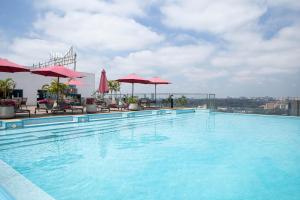 a large swimming pool with red umbrellas on a building at The Skies by YourHost, Westlands Nairobi in Nairobi