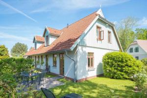 una casa bianca con tavolo e sedie nel cortile di Ferienhaussiedlung Strandperlen Buchenhof 4d (Typ IV) a Wustrow