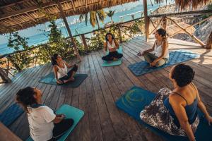 a group of women sitting in a yoga class on the beach at Namaste Beach Club & Hotel in Tierra Bomba