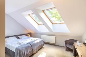 a attic bedroom with a bed and two windows at Pokoje Gościnne Cichosza in Szklarska Poręba