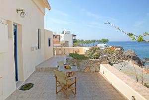 a patio with a table and chairs and the ocean at On The Beach Apartments in Hora Sfakion