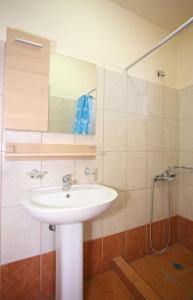 a bathroom with a white sink and a shower at On The Beach Apartments in Hora Sfakion