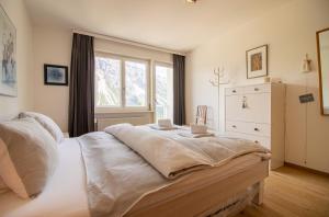 Schlafzimmer mit einem großen weißen Bett und einem Fenster in der Unterkunft Viktoria B42 by Arosa Holiday in Arosa