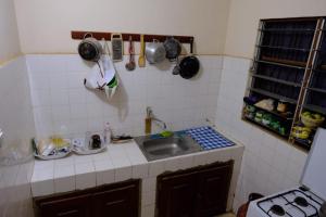 kuchnia ze zlewem oraz garnkami i patelniami na ścianie w obiekcie Studio tout équipé au sein de l'ONG Okouabo w mieście Parakou