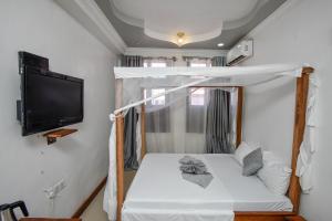 a bed in a room with a tv and a bed with a canopy at Kuti Hotel Stone Town in Ngambo +18 photos