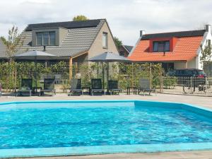 a swimming pool in front of a house at Bungalow 36 op Recreatiepark De Wielen in Sint Maarten