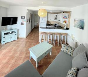 a living room with a couch and a kitchen at Salitre Ocean Sunset in El Cotillo