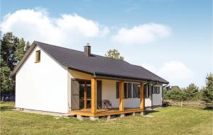a small white cottage with a black roof at Cozy Home In Kolczewo With Kitchen in Kołczewo