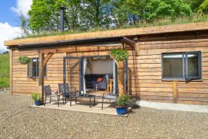 a small wooden cabin with chairs and a couch at Llwyn-Teg Log Cabin in Whitland