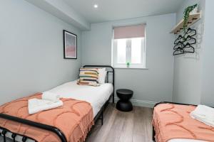 1 dormitorio con 2 camas y ventana en NEW Nr Bmth town and beach, 2 bed, garden & parking - Sea Esta, en Bournemouth