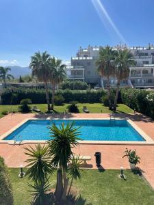 einem großen Pool mit Palmen und einem Gebäude in der Unterkunft Blue Oliva Nova MET & Golf in Oliva