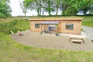 a small cabin with a picnic table and a bench at Llwyn-Teg Log Cabin in Whitland