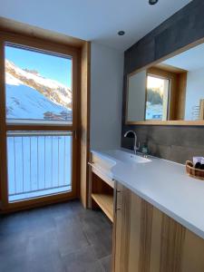 a bathroom with a sink and a window with snow covered mountains at Dahoam - neue Ferienwohnung mit Kamin und Sauna in Schröcken
