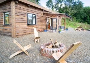 a log cabin with chairs and a fire pit in front of it at Llwyn-Teg Log Cabin in Whitland